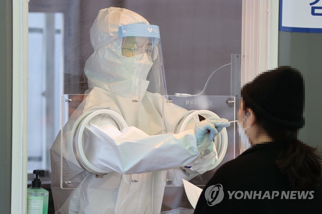 A health worker conducts a screening test at a temporary screening center set up in front of Seoul Station in central Seoul on Jan. 23, 2021. (Yonhap)