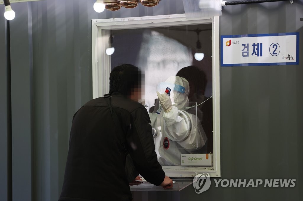 A medical worker collects a specimen for coronavirus testing at a temporary clinic in front of Seoul Station on Jan. 24, 2021, as the third wave of the COVID-19 pandemic, which started in November last year, shows signs of a let-up after peaking with daily cases of 1,241 on Dec. 25. (Yonhap)