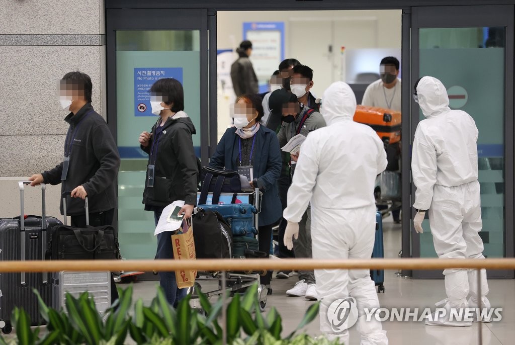 Health workers clad in protective suits guide arrivals from India at Incheon International Airport, west of Seoul, on May 7, 2021. (Yonhap)