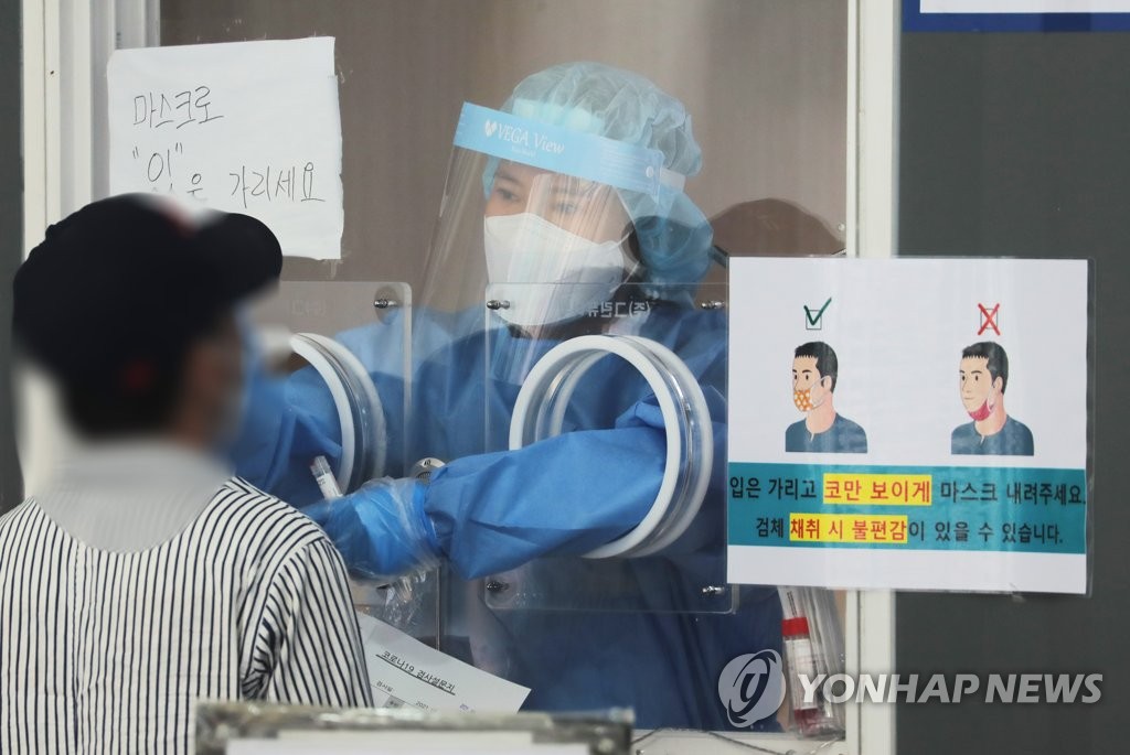A health worker clad in protective gear collects a sample from a citizen at a makeshift virus testing clinic in Seoul on June 7, 2021. (Yonhap)