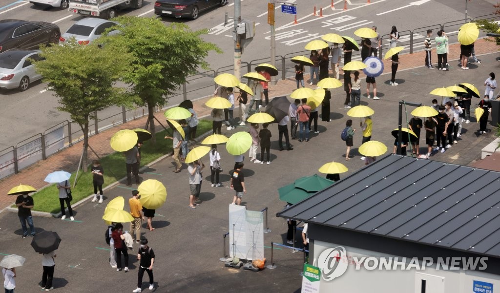 大勢の人が日傘を差して検査の順番待ちをしている（資料写真）＝（聯合ニュース）