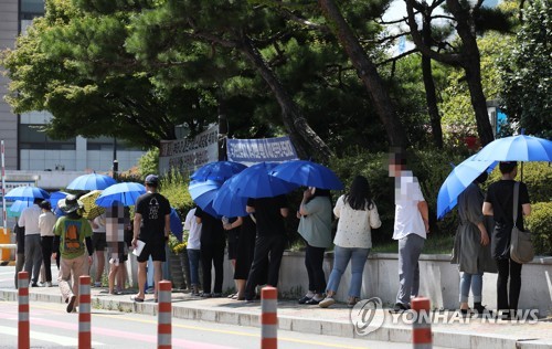 Des gens attendent avant de se soumettre à un test de dépistage du nouveau coronavirus (Covid-19). (Photo d'archives Yonhap)