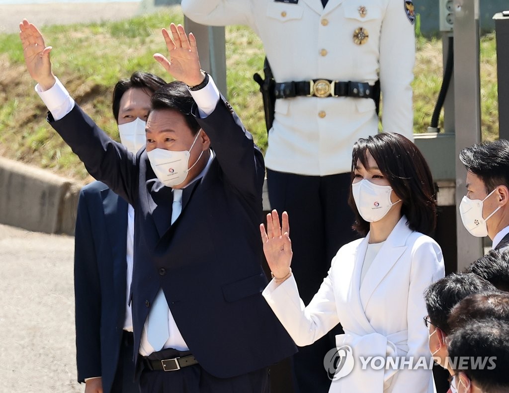 President Yoon Suk-yeol and his wife, Kim Keon-hee, wave toward people lining up along a road while entering the presidential office in Seoul on May 10, 2022, right after his inaugural ceremony. (Pool photo) (Yonhap)