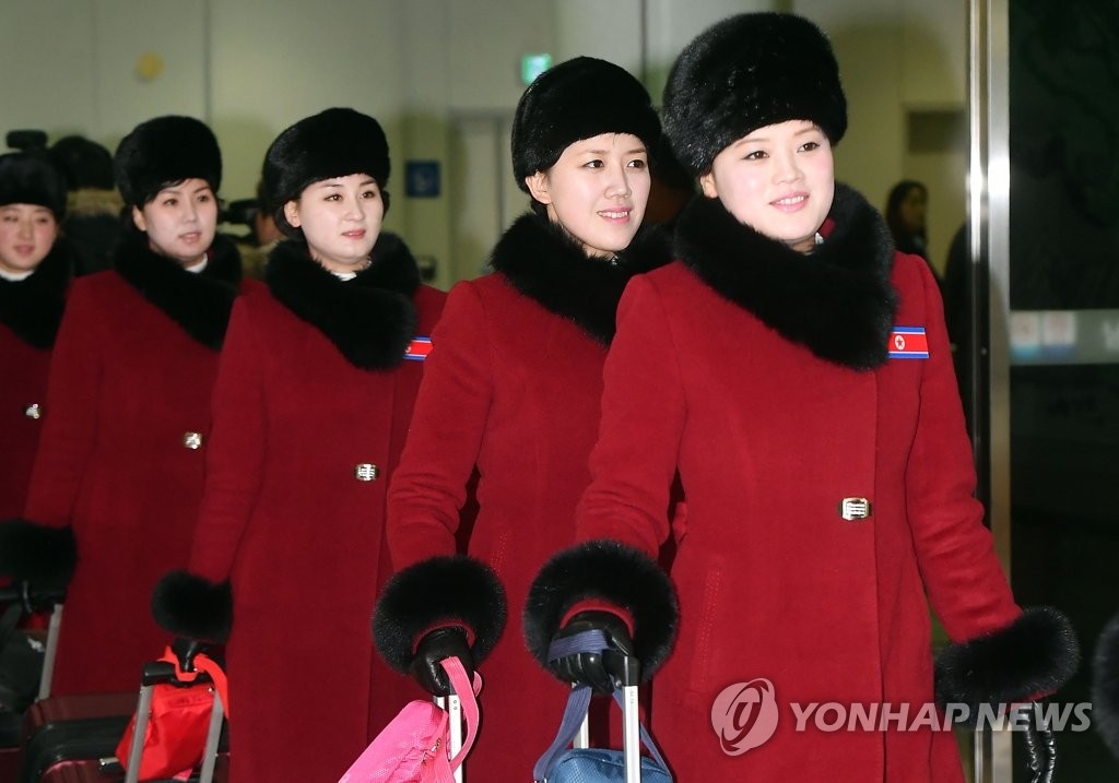 2月7日上午，在京畿道坡州市都罗山南北出入境事务所（CIQ），身着红衣，胸戴朝鲜国旗徽章的朝鲜拉拉队成员走入韩国境内。（韩联社/联合采访团）