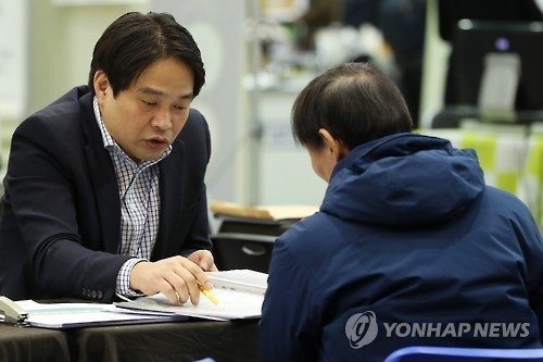 This file photo, taken on Dec. 28, 2016, shows a local adviser (L) offering advice to a client at a local business fair on retirement programs in Seoul. (Yonhap)
