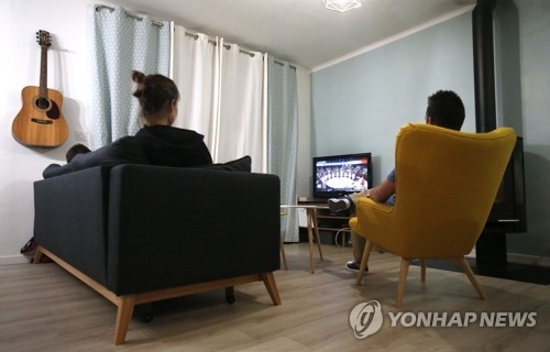 This undated photo shows people watching TV at home. (Yonhap)