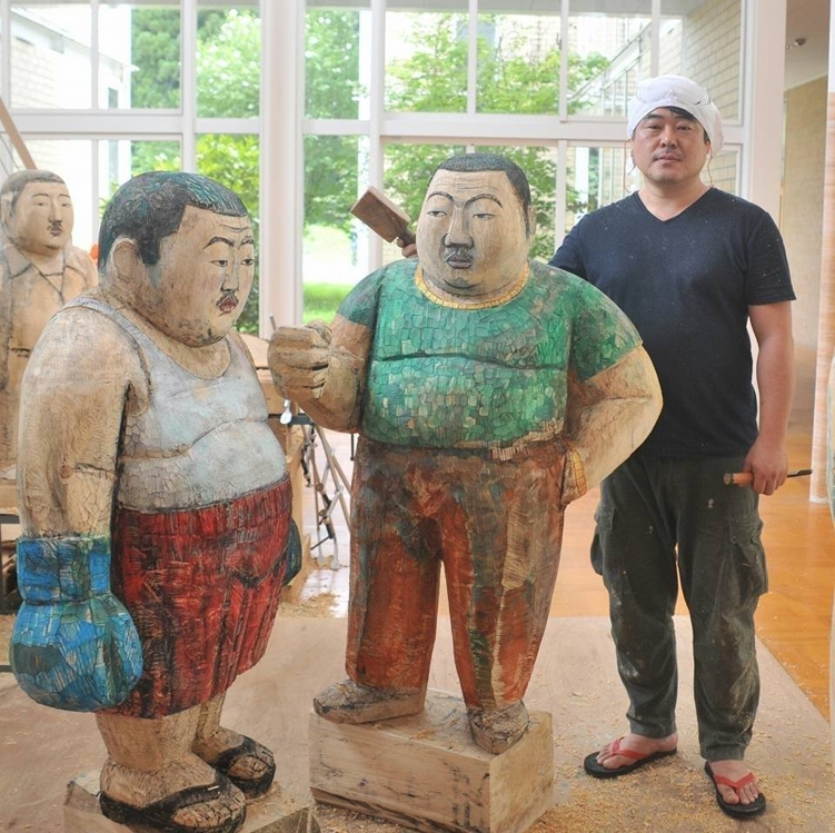 This undated photo, taken from Kim Won-geun's Facebook page on June 8, 2017, shows the sculptor standing next to his sculptures. (Yonhap)