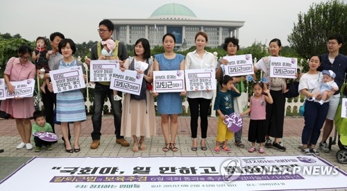 Activists from a civic group called "Political Mothers" stage a rally in front of the National Assembly to call for the parliamentary passage of an extra budget bill and the bill aimed at preventing overtime work on June 21, 2017. (Yonhap)