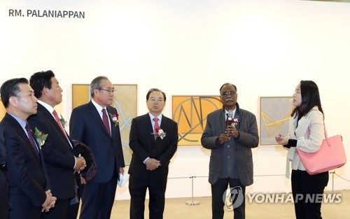 Indian artist Rm. Palaniappan (2nd from R) talks in front of his works at the Busan International Art Fair at the Busan Exhibition and Convention Center in Busan on Dec. 7, 2017. (Yonhap)