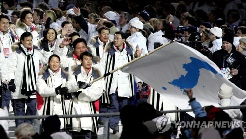 In this file photo taken Feb. 12, 2006, athletes from South and North Korea march in together at the opening ceremony of the Torino Winter Olympics in Torino, Italy. South Korean speed skater Lee Bo-ra (front L) and North Korean figure skater Han Jong-in hold the Korean Peninsula Flag together. (Yonhap)