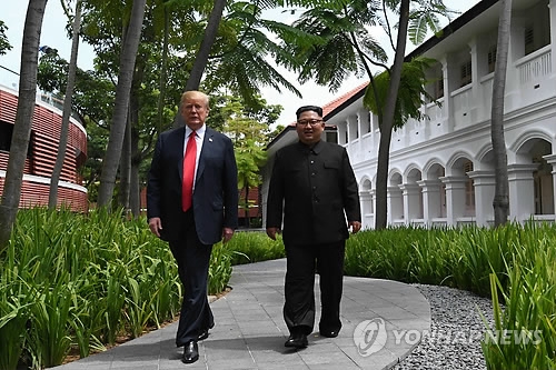 U.S. President Trump (L) and North Korean leader Kim Jong-un walk together after summit talks at the Capella Hotel in Singapore on June 12, 2018. (AFP-Yonhap)