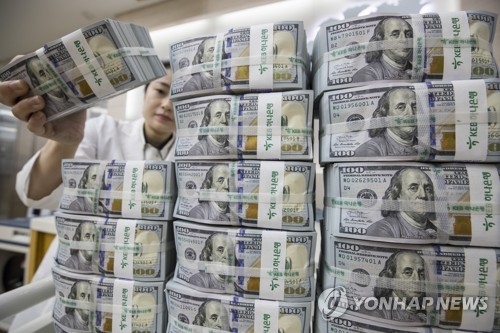 A bank employee piles bundles of U.S. 100 dollar bills at a Seoul office of KEB Hana Bank on July 4, 2018. (Yonhap)