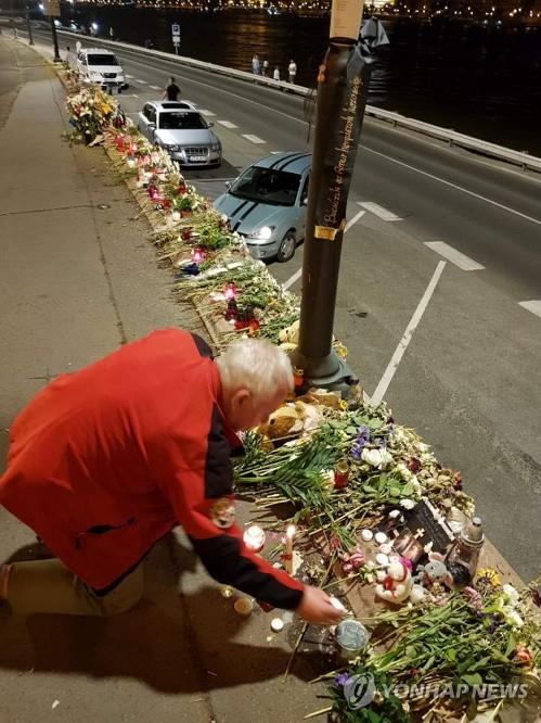 A Hungarian citizen lays a flower at a makeshift altar near the Margit Bridge over the Danube River in Budapest on June 7, 2019, to pay tribute to the victims of a deadly boat sinking. (Yonhap)