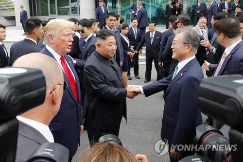South Korean President Moon Jae-in (R) shakes hands with North Korean leader Kim Jong-un (C) in Panmunjom on June 30, 2019. (Yonhap)