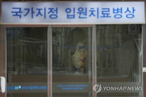 A staff member at Seoul National University Hospital in Bundang, south of Seoul, wearing a full protective suit waits to check people as they enter the building on Jan. 29, 2020. (Yonhap)