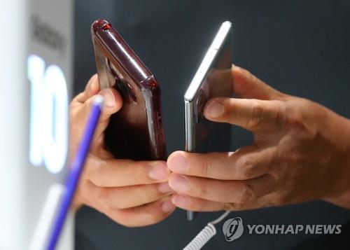 In this file photo taken on Aug. 8, 2019, a customer looks at smartphones at Samsung Electronics. Co.'s retail store in Seoul. (Yonhap)