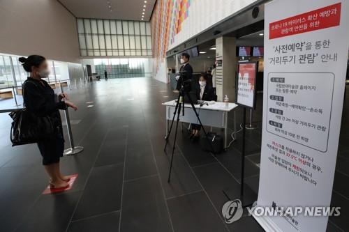 An official at the Seoul branch of the National Museum of Modern and Contemporary Art conducts a fever test on a visitor on May 7, 2020. (Yonhap)