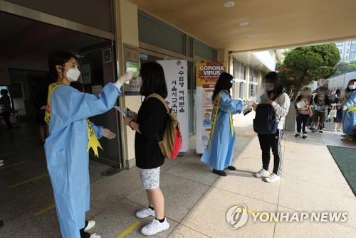 Applicants for this year's school qualification examination have their temperatures checked at a middle school in Seoul on May 23, 2020. The exam for a general equivalency diploma was supposed to be held in April but was delayed twice due to the coronavirus. (Yonhap)