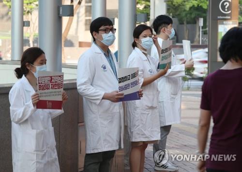 Doctors hold up signs criticizing the government at a Seoul hospital on Aug. 26, 2020, as tens of thousands of doctors went on a full-scale strike nationwide for a three-day run earlier in the day in protest of the government's medical workforce reform. (Yonhap) 