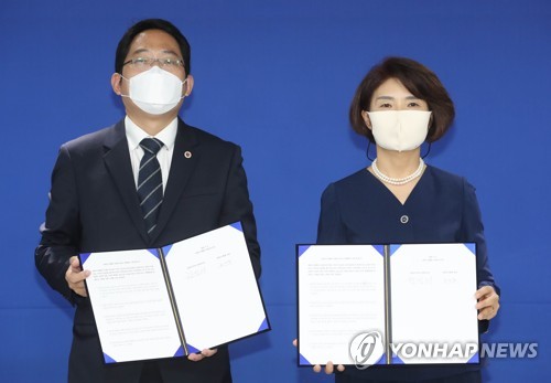 Korean Medical Association head Choi Dae-zip (L) and ruling Democratic Party policy committee chief Rep. Han Jeoung-ae hold up signed agreements outlining future talks to resolve the government's medical reform plan and end the strike by doctors, in Seoul on Sept. 4, 2020. (Yonhap) 