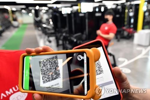 This photo, provided by Suwon City, south of Seoul, shows an official at a fitness center in the city checking a smartphone QR code-based entry log on June 10, 2020, the first day of the mandatory QR code-based registration of visitors at bars, clubs and other entertainment facilities across the country to stem the spread of the new coronavirus. (PHOTO NOT FOR SALE) (Yonhap)