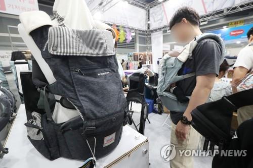 A man carries an infant in a baby carrier at a promotion event for baby and kids products in Seoul on July 4, 2019. (Yonhap) 