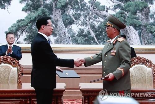 South Korean Defense Minister Song Young-moo (L) shakes hands with his North Korean counterpart, No Kwang-chol, after signing a military agreement in Pyongyang on Sept. 19, 2018, in this image from live TV coverage shown at the press center in Seoul. The two Koreas agreed to halt military drills targeted at each other and to set up buffer zones along their air, land and sea borders. (Yonhap)