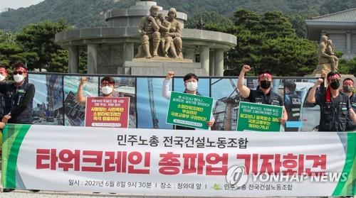 Tower crane operators belonging to the Korean Construction Workers' Union shout slogans during a news conference held in front of Cheong Wa Dae in Seoul on June 8, 2021, to announce their general strike. (Yonhap)