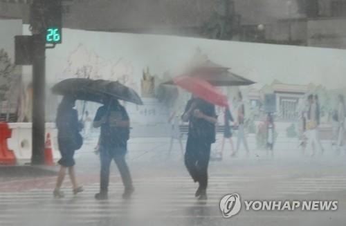 People walk near Gwanghwamun Square in downtown Seoul on June 23, 2021, amid sudden rain showers. (Yonhap)