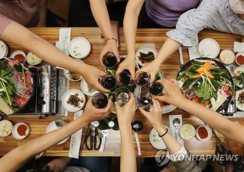 A group of people toast while eating out together in the southwestern city of Gwangju on June 18, 2021. In Gwangju, private gatherings of up to eight people are allowed under current social distancing rules. (Yonhap)