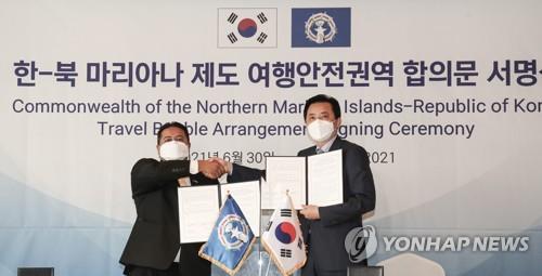 South Korea's Vice Transport Minister Hwang Seong-kyu (R) shakes hands with Saipan's governor Ralph Torres after signing a "travel bubble" agreement in Seoul on June 30, 2021. (Yonhap)