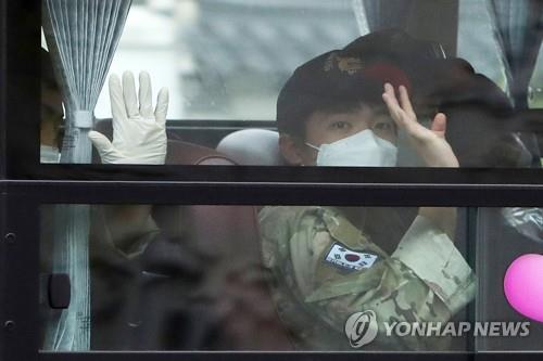 A member of the Cheonghae unit waves to the press from a bus at an air base in Seongnam, south of Seoul, on July 20, 2021. The 301-strong unit on an anti-piracy mission in waters off East Africa was flown home after 247 members tested positive for COVID-19. (Yonhap)
