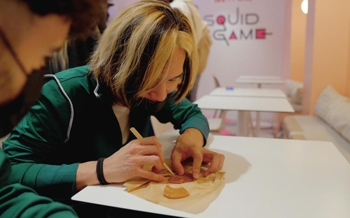 This photo, provided by Netflix France, shows visitors at a pop-up store for the Netflix series "Squid Game" in Paris playing a game of "dalgona bbobggi" on Oct. 3, 2021. (PHOTO NOT FOR SALE) (Yonhap)