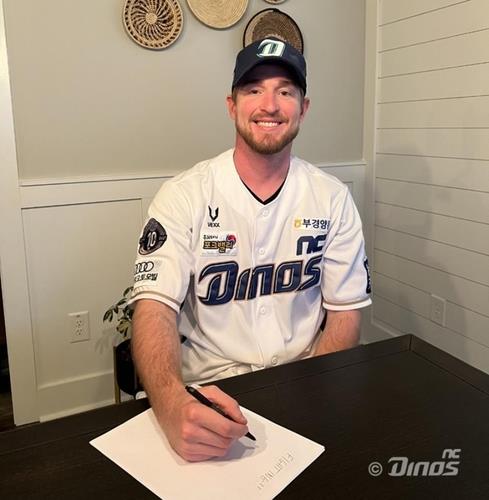 Wes Parsons of the NC Dinos smiles as he signs a new contract with the Korea Baseball Organization club, in this photo provided by the Dinos on Dec. 21, 2021. (PHOTO NOT FOR SALE) (Yonhap)
