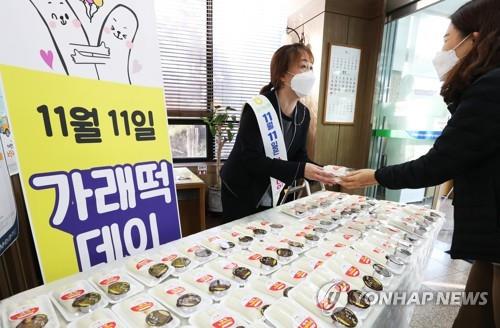 In this file photo, an employee of NH Nonghyup Bank shows packs of "garaetteok," a Korean rice cake stick, during an event in Suwon, south of Seoul, on Nov. 10, 2020, to treat passers-by to the complimentary foodstuff as part of efforts to promote rice consumption ahead of Farmers' Day the following day. (Yonhap)