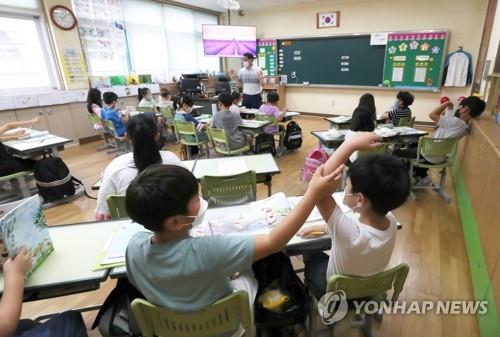 Students sit at desks that no longer have plastic dividers meant to stop spread of the coronavirus at an elementary school in Chuncheon, Gangwon Province, on June 28, 2022. (Yonhap)