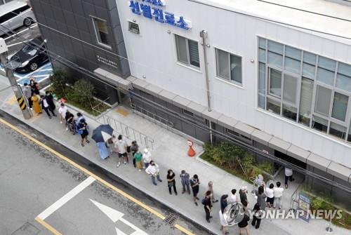 This photo, provided by a ward office in the southwestern city of Gwangju, shows people waiting to undergo COVID-19 tests in the city on Aug. 16, 2022. (PHOTO NOT FOR SALE) (Yonhap)