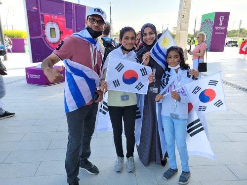 A family of four from India, with father Zakir (L), poses with Uruguayan and South Korean flags before the two countries' Group H match at the FIFA World Cup at Education City Stadium in Al Rayyan, west of Doha, on Nov. 24, 2022. (Yonhap)