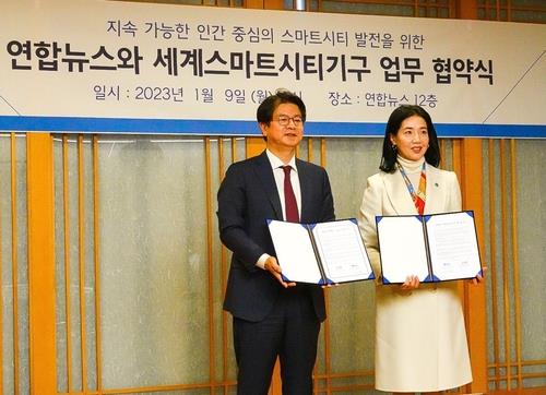 Seong Ghi-hong (L), president and CEO of Yonhap News Agency, and Park Jung-sook, secretary general of the World Smart Sustainable Cities Organization, pose after signing a cooperation agreement at Yonhap&apos;s headquarters in Seoul on Jan. 9, 2023. (Yonhap)