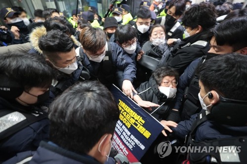 An activist from Solidarity Against Disability Discrimination is surrounded by Seoul subway workers and police at Dongdaemun History & Culture Park Station on Subway Line 4 on January 3, 2023. (Yonhap)