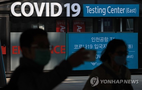 Esta foto de archivo, tomada el 29 de marzo de 2023, muestra a personas caminando frente a un centro de pruebas de COVID-19 en el Aeropuerto Internacional de Incheon, al oeste de Seúl.  (Yonhap)