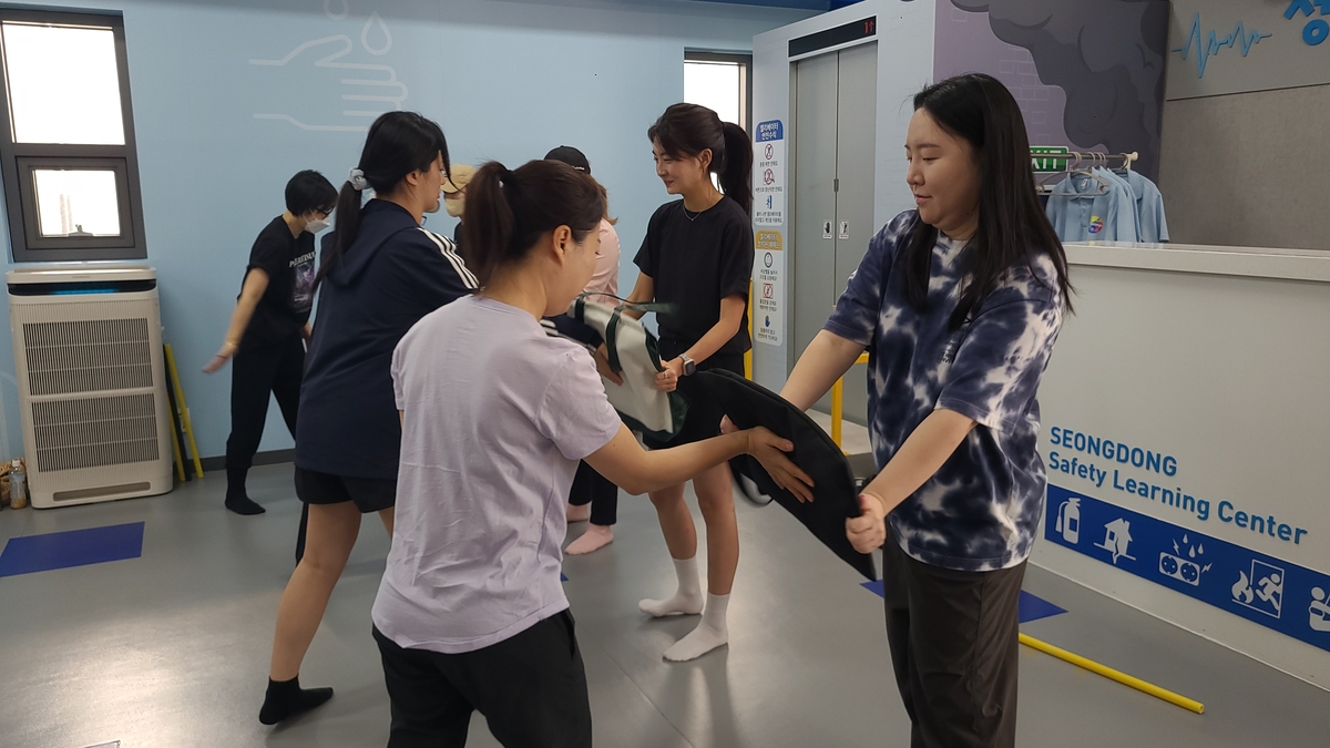 Students practice how to defend themselves from an attack using a bag during a self-defense class provided by the Seongdong Safety Learning Center on Sept. 2, 2023. (Yonhap)