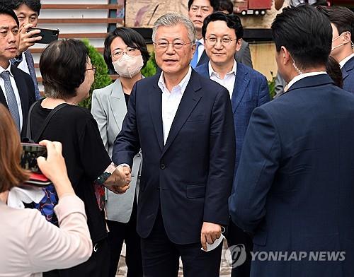 Former President Moon Jae-in (C) shakes hands with a supporter while leaving a hospital on Sept. 19, 2023, after visiting opposition leader Lee Jae-myung on a hunger strike. (Yonhap)