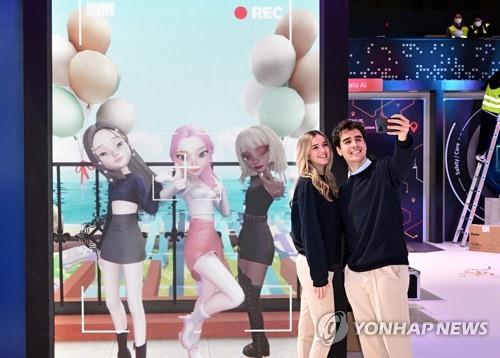 People take a photo in front of SK Telecom Co.'s exhibition booth for its metaverse service ifland on Feb. 26, 2023, ahead of its opening at the Mobile World Congress 2023 in Barcelona, Spain. (Pool photo) (Yonhap)