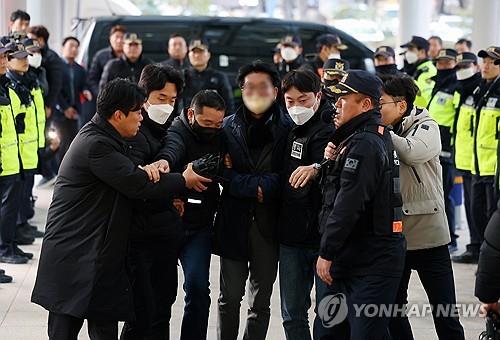 A man (4th from L, blurred) is taken by police investigators from Gangseo Police Station to Busan Metropolitan Police Agency in Busan on Jan. 2, 2024. The suspect is accused of stabbing opposition leader Lee Jae-myung in the neck during the politician's visit to Busan. (Yonhap)