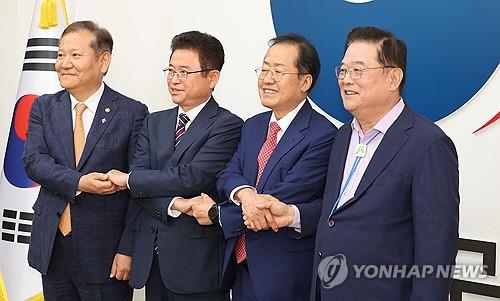 Daegu Mayor Hong Joon-pyo (2nd from R), North Gyeongsang Gov. Lee Cheol-woo (2nd from L), Minister of the Interior and Safety Lee Sang-min (L) and Woo Dong-gi, chairman of the Presidential Committee for Decentralization and Balanced Development, pose at the Seoul Government Complex on Oct. 21, 2024, after agreeing to merge Daegu and North Gyeongsang by July 2026. (Pool photo) (Yonhap)