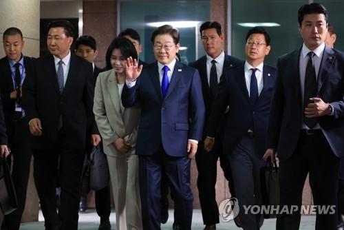 Democratic Party presidential candidate Lee Jae-myung (C) waves to his supporters outside his residence in Incheon, west of Seoul, on June 3, 2025. Standing beside Lee on his right is his wife, Kim Hye-kyung. (Yonhap)