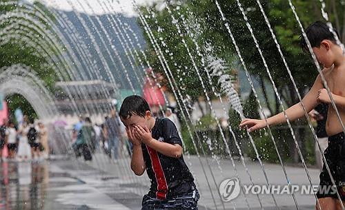 Children try to cool off at a tunnel fountain on Gwanghwamun Square in central Seoul on June 30, 2025, amid a heat wave advisory issued for the entire capital. (Yonhap)