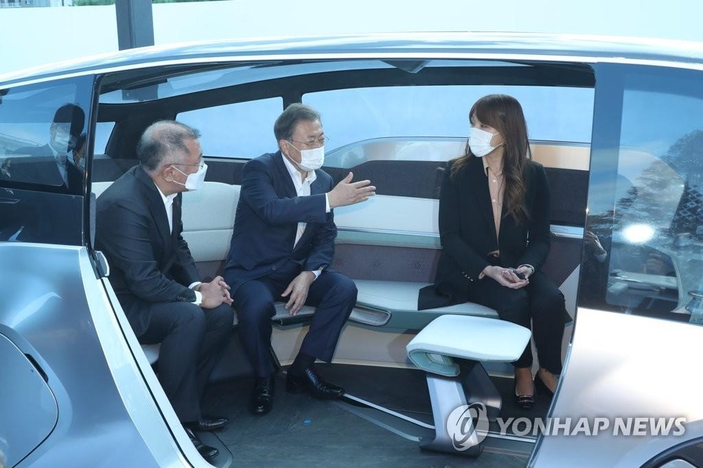 Le président Moon Jae-in (au c.) essaie un véhicule autonome pour un service d'autopartage M.Vision S avec le chef du groupe Hyundai Motor, Chung Euisun (à g.), après avoir participé à un dialogue sur les stratégies pour les futures voitures dans l'usine de l'entreprise à Ulsan, dans le sud-est du pays, le vendredi 30 octobre 2020.