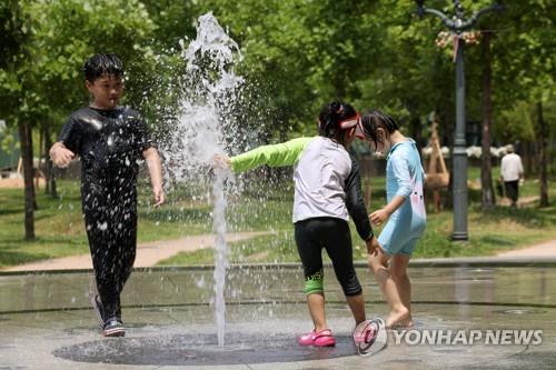 Des enfants s'amusent dans une fontaine d'un parc d'attractions à Damyang, à 250 kilomètres au sud de Séoul, le 20 juin 2022.
